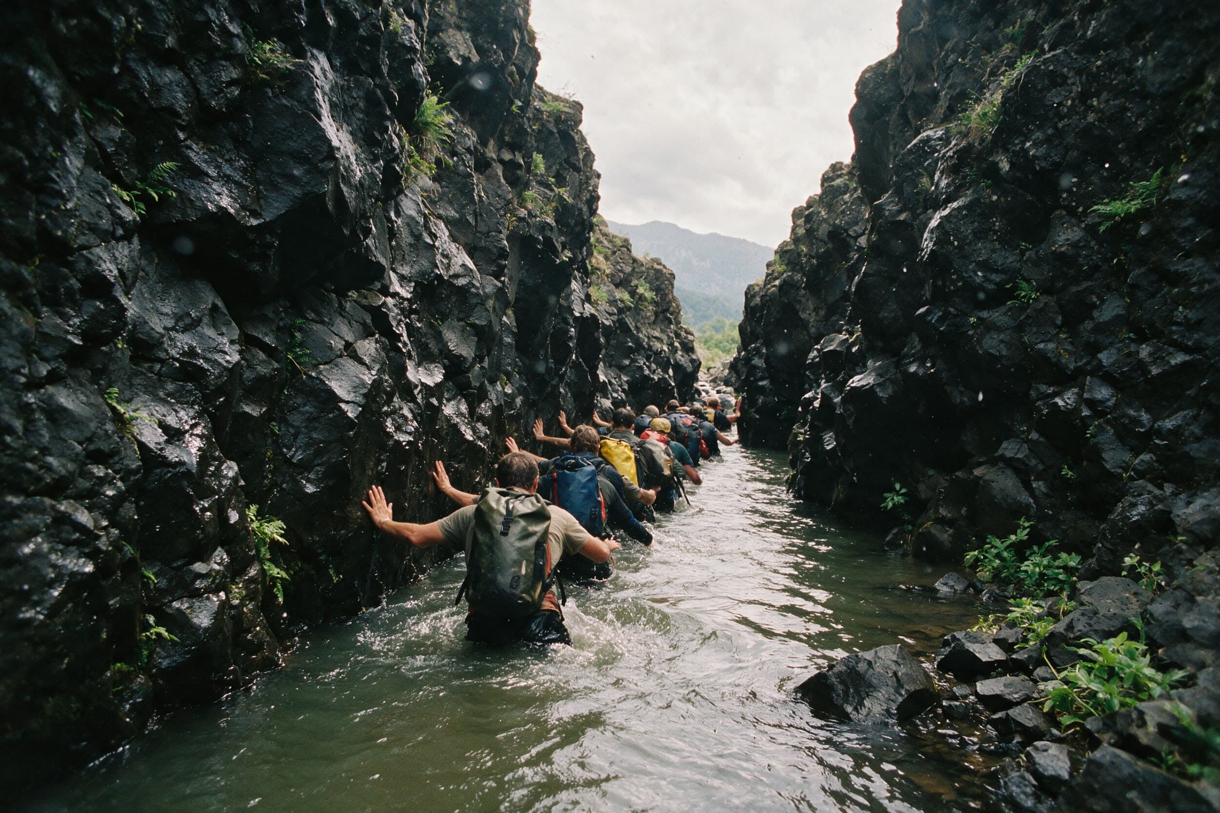 Gruppe watet im Gänsemarsch durch hüfttiefes Wasser einer engen Schlucht