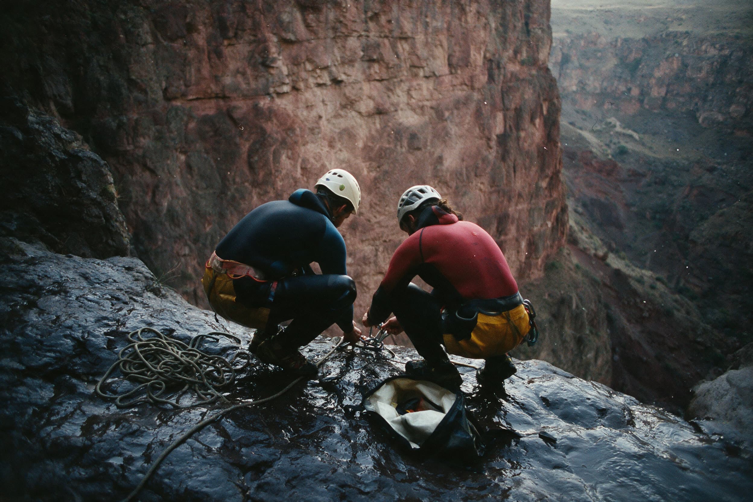 Twee canyoneers bouwen op een natte richel boven een trap een anker