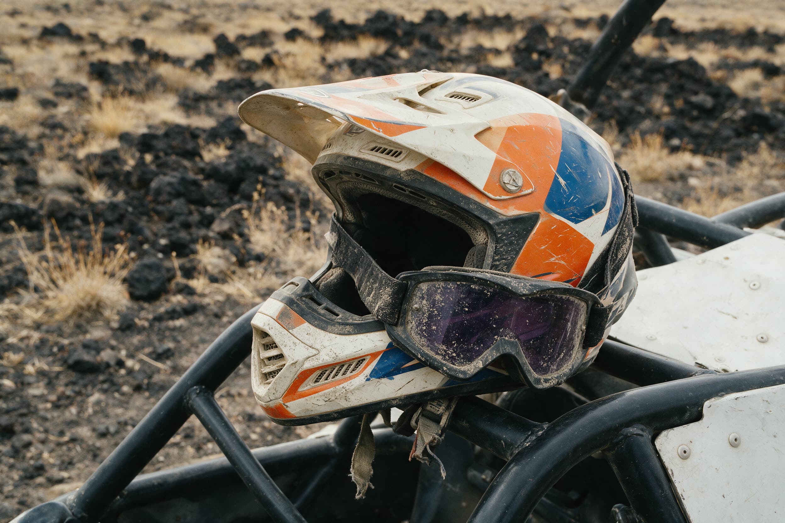 Zerkratzter Integralhelm und staubige Brille auf dem Überrollkäfig eines Buggys
