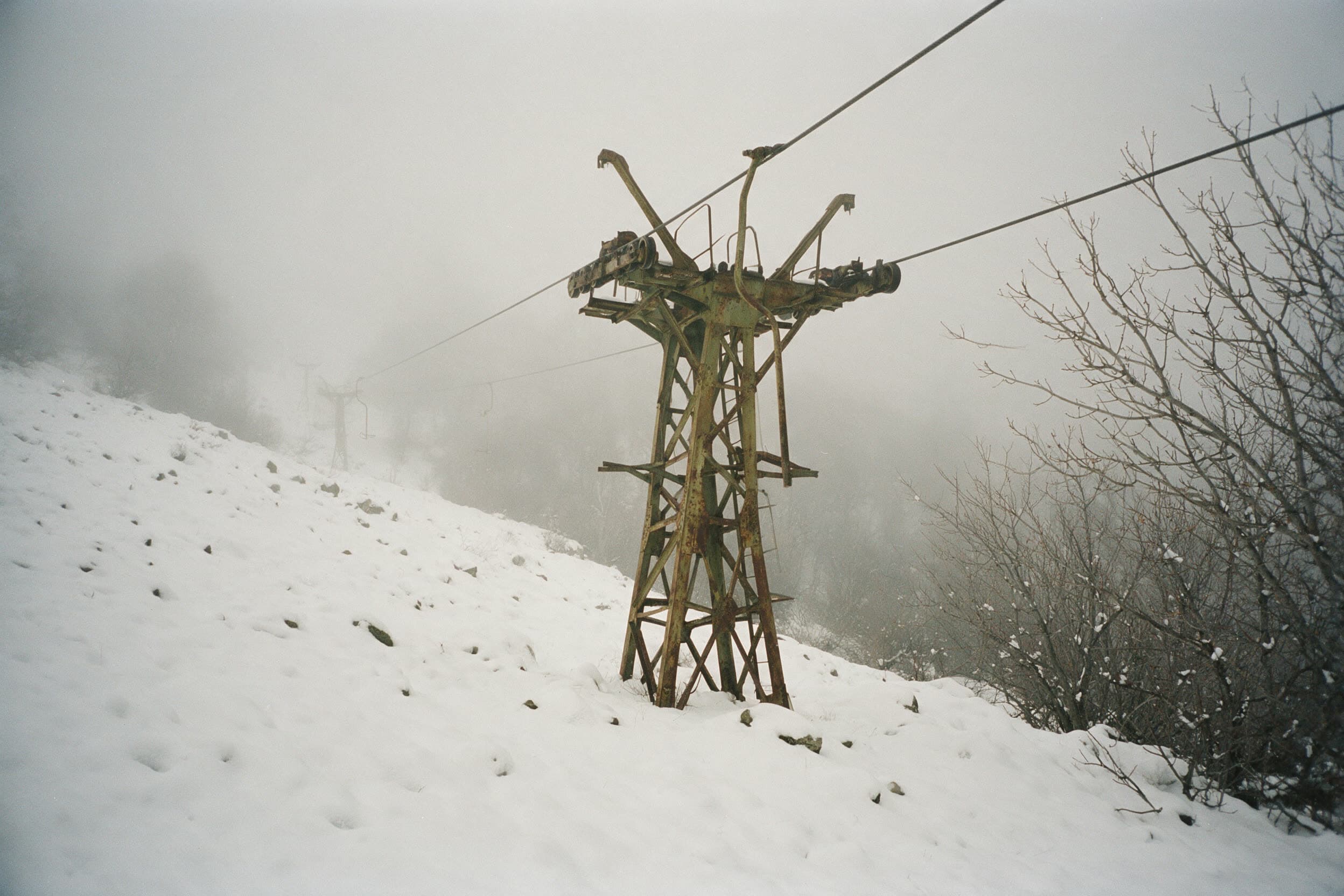 Rostende sowjetische Liftstütze im Schnee und Nebel