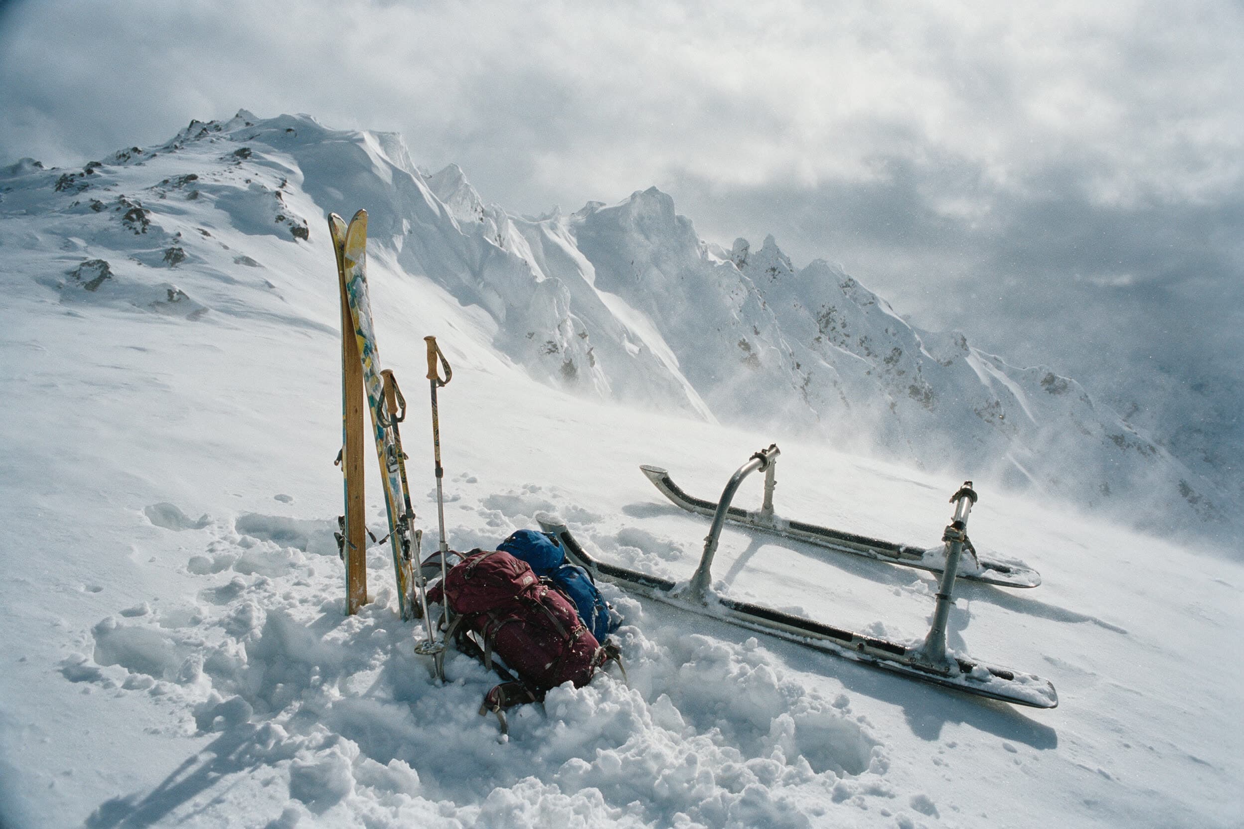 Ski und Stöcke aufrecht im Schnee neben der Hubschrauberkufe