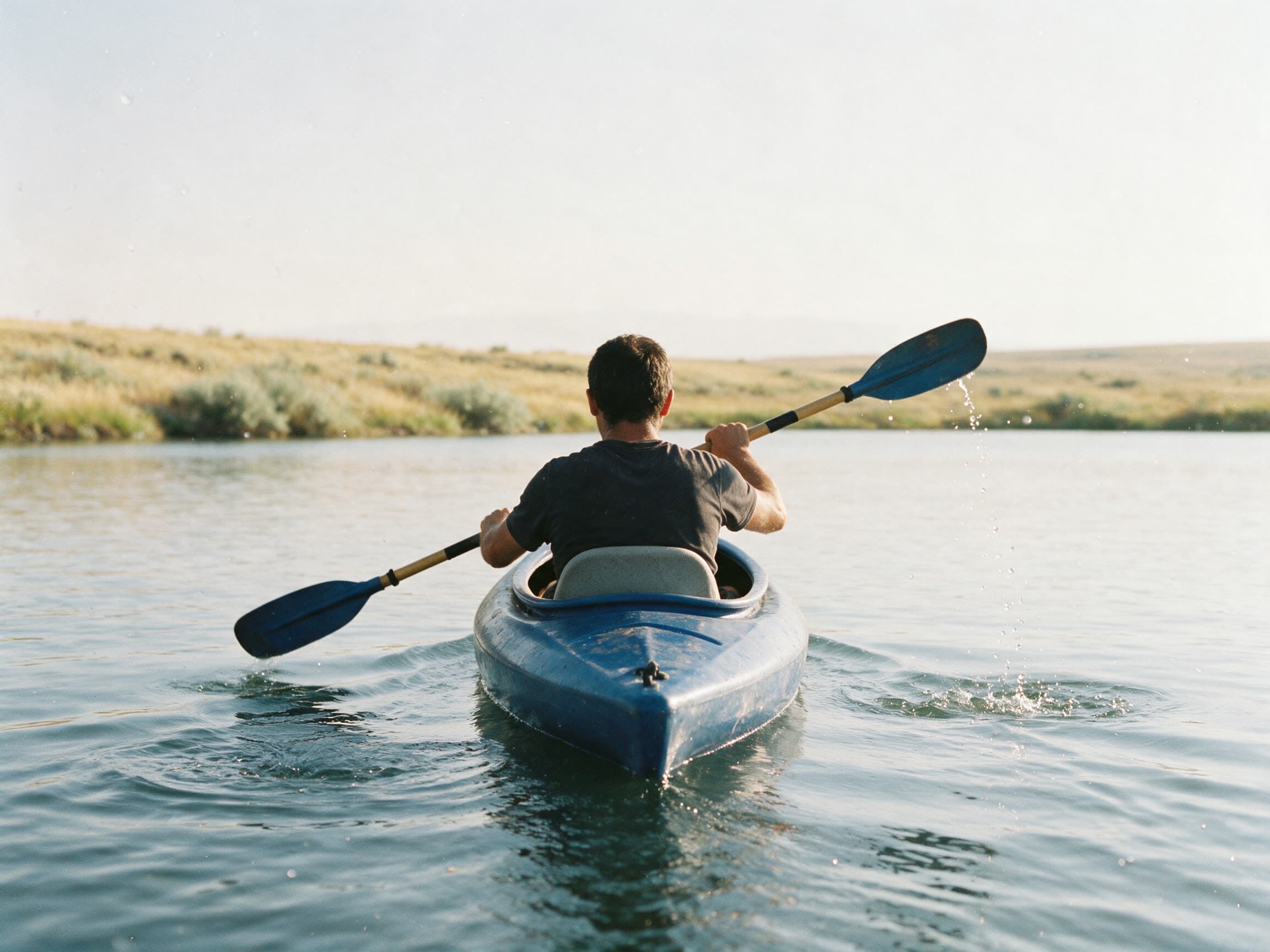Kajak auf flachem Wasser in der Region Schirak, der Paddler von hinten