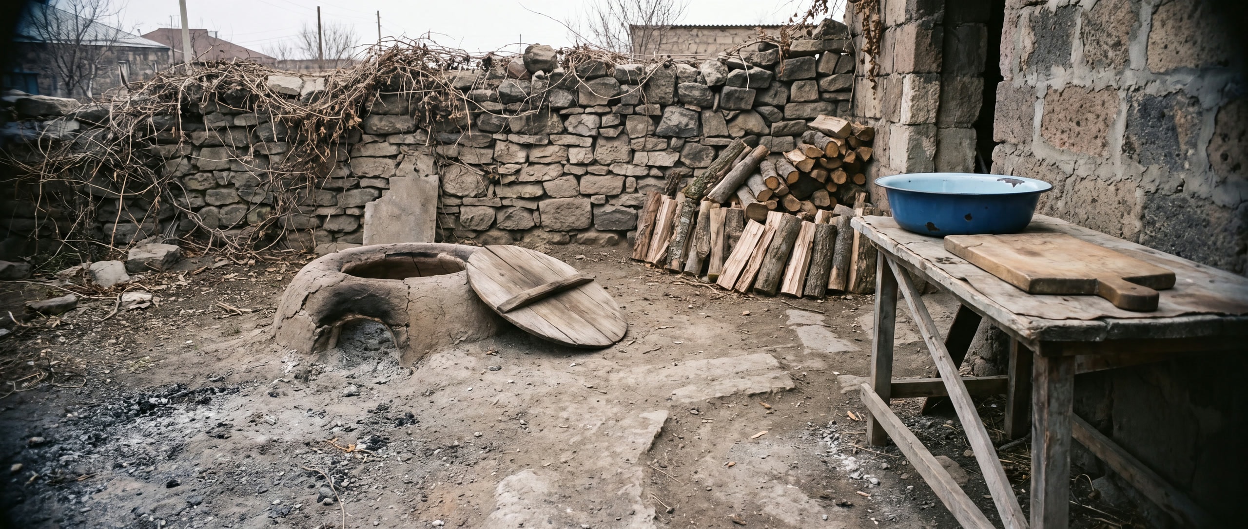 Armenische Dorfküche im Freien mit eingelassenem Tonir und gestapeltem Brennholz