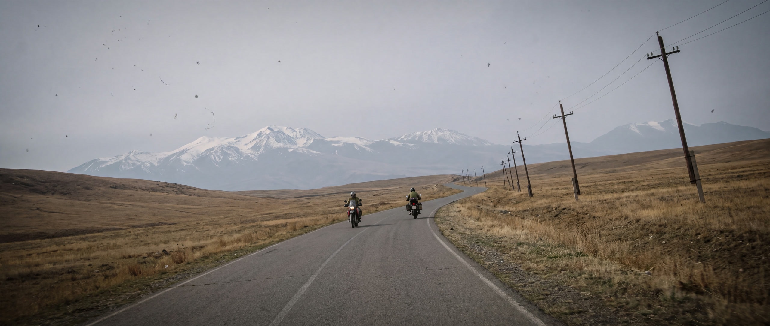 Zwei Reisemotorräder winzig auf einer leeren Passstraße durch armenische Hochweide