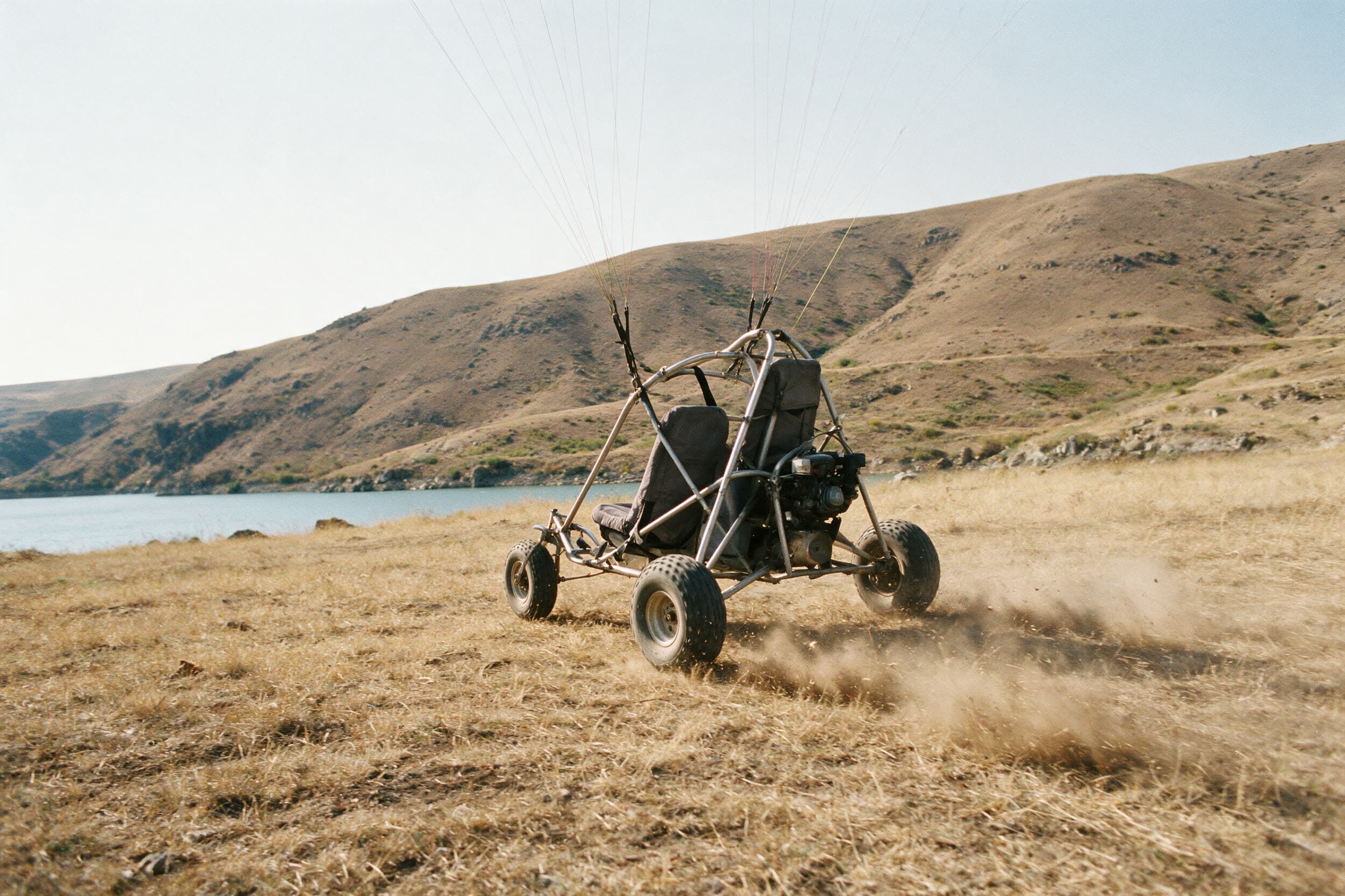 Motorschirm-Trike rollt über trockenes Gras am Azat-Stausee