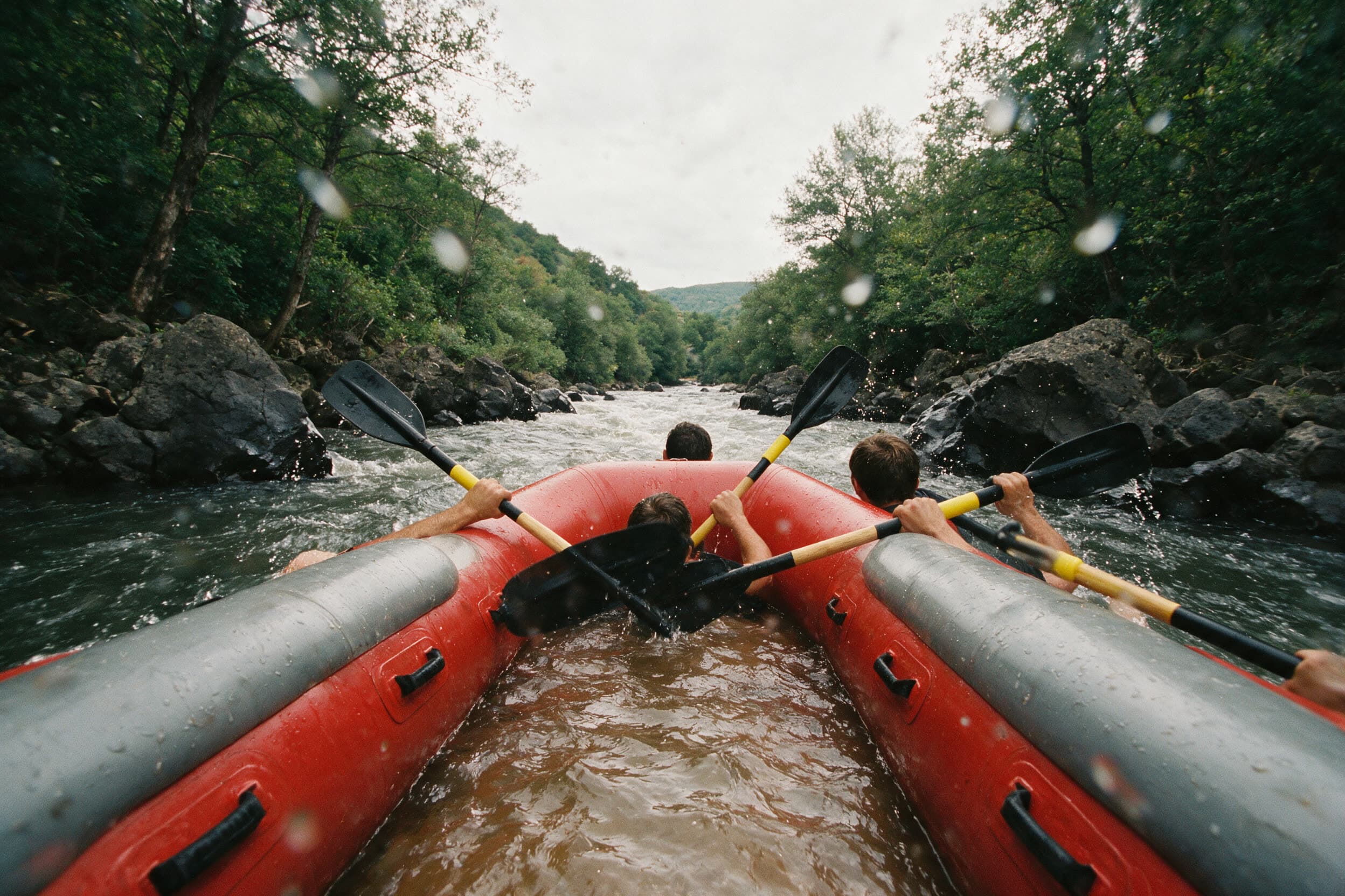 Blick vom Heck des Schlauchboots über die Schultern der Paddler auf den Fluss