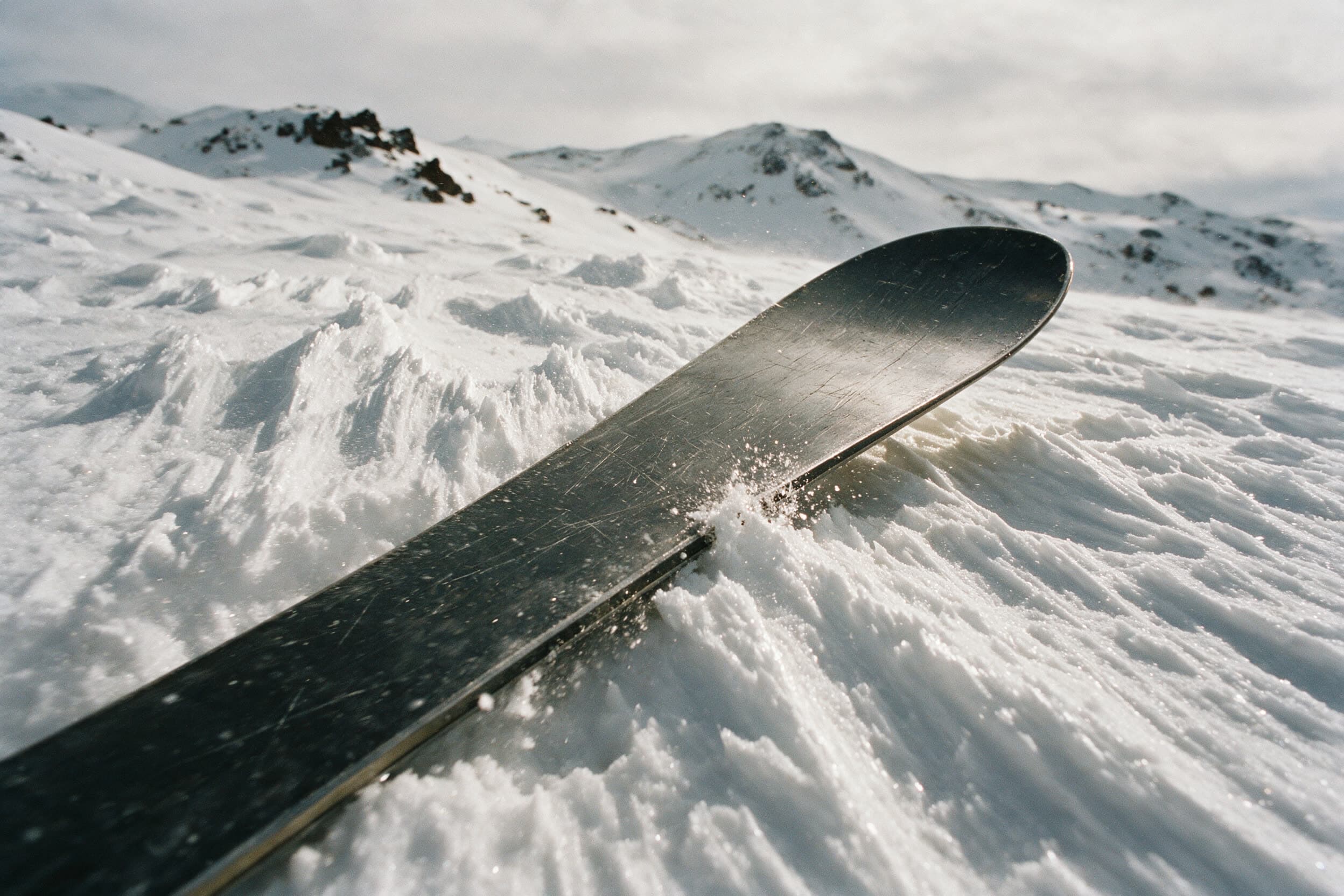 Snowboardkante schneidet durch windgeformte Schneerippen