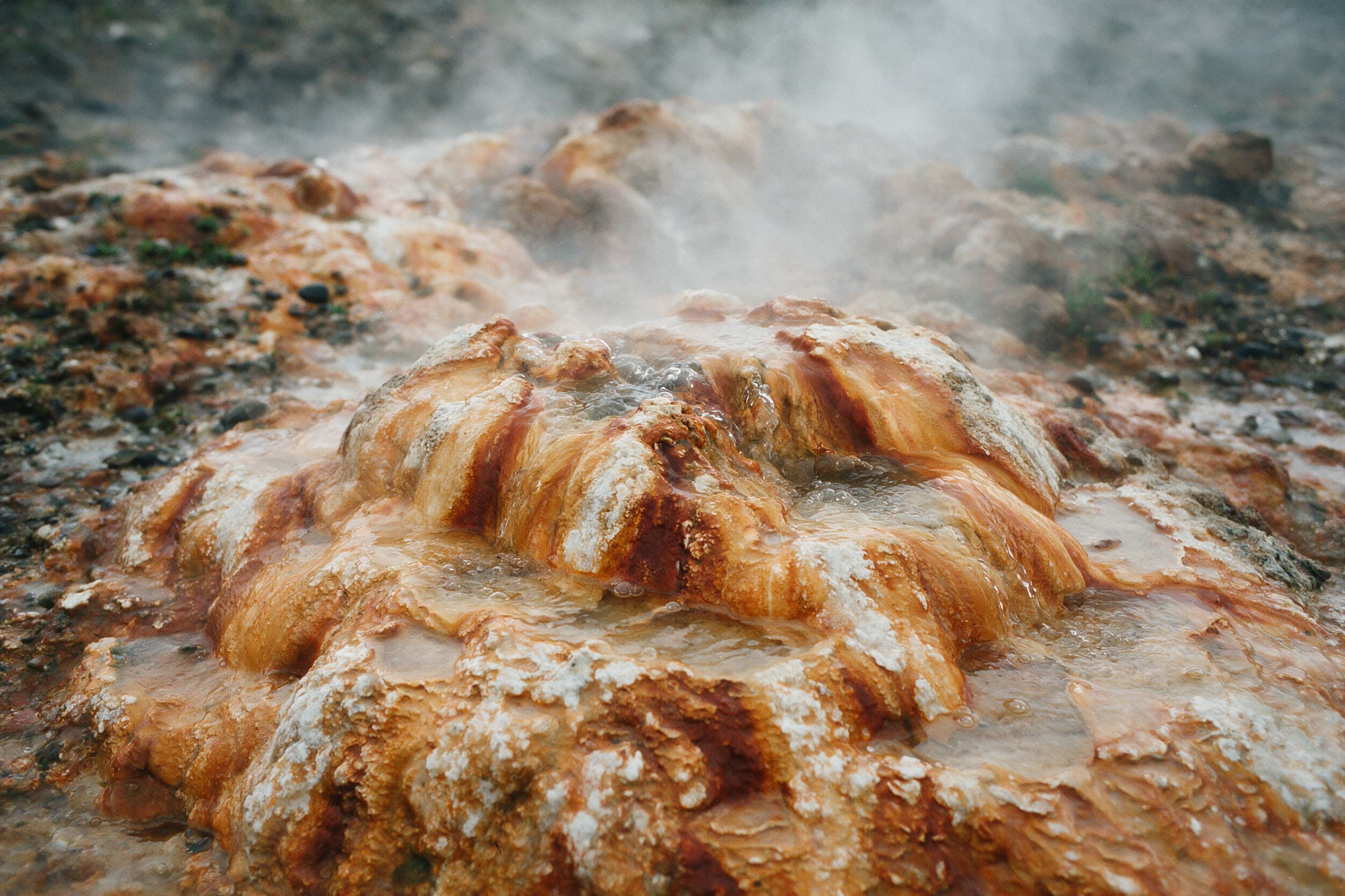 Une croûte minérale orange et blanche autour d'un exutoire de source chaude