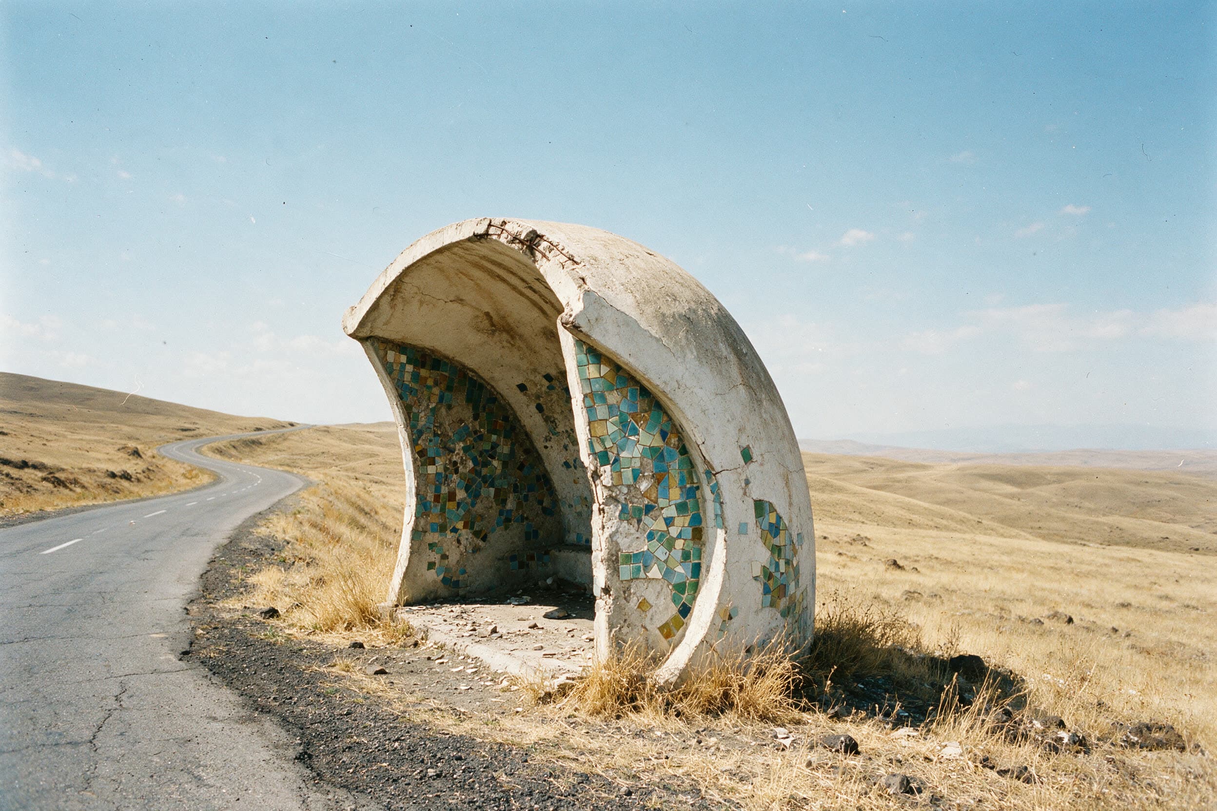 Un abribus soviétique en béton sculptural, revêtu de mosaïque, sur une route d'altitude déserte