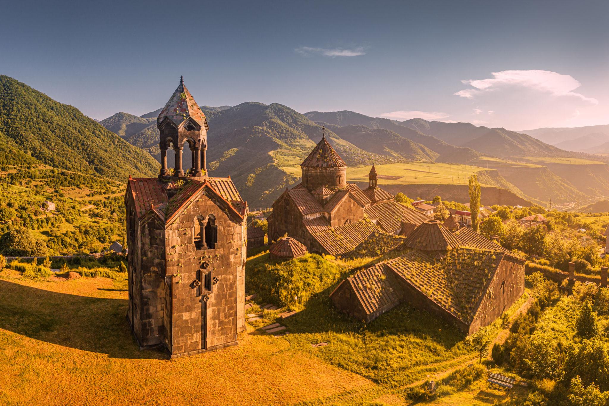 Haghpat monastery and its bell tower glowing at sunset above the green hills of Lori