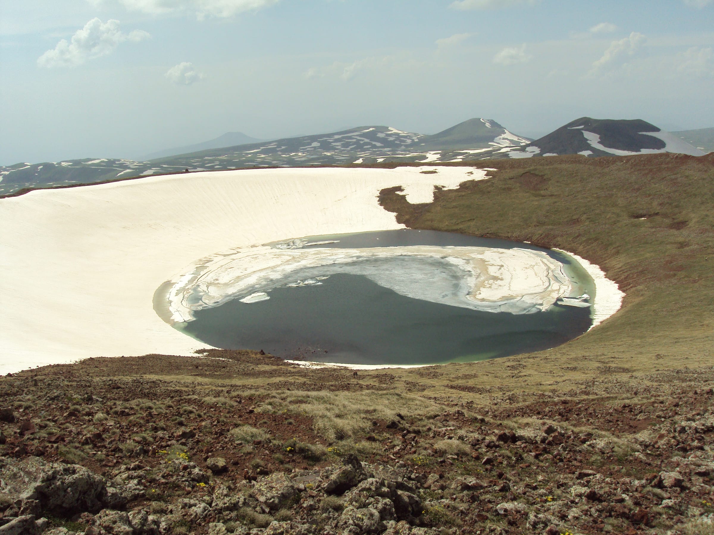 Crater lake of the Azhdahak volcano in the Geghama range, still half covered in snow
