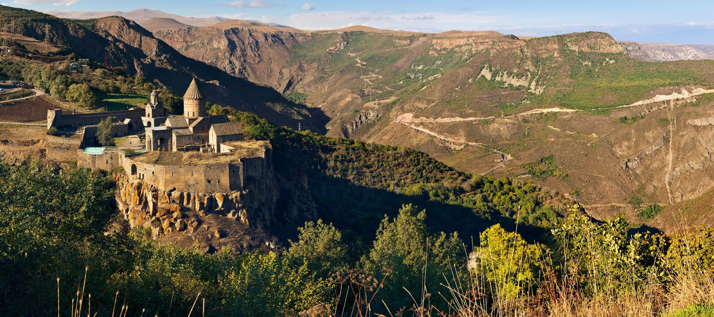 Wide view of Tatev Monastery on its plateau above the Vorotan Gorge, mountains beyond